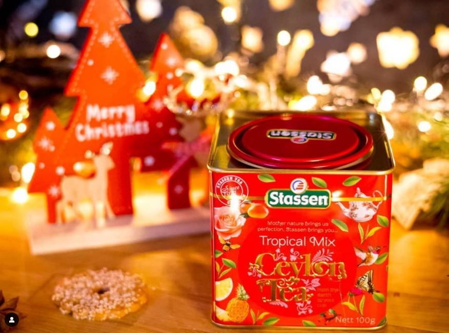 Herbata Stassen Tropical Mix w puszce na tle świątecznych dekoracji.