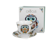 Filiżanka porcelanowa ze spodkiem Sowa Etno ustawiona przed ozdobnym pudełkiem.