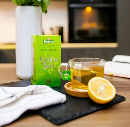 Herbata zielona Stassen Green Tea z filiżanką naparu i cytryną.