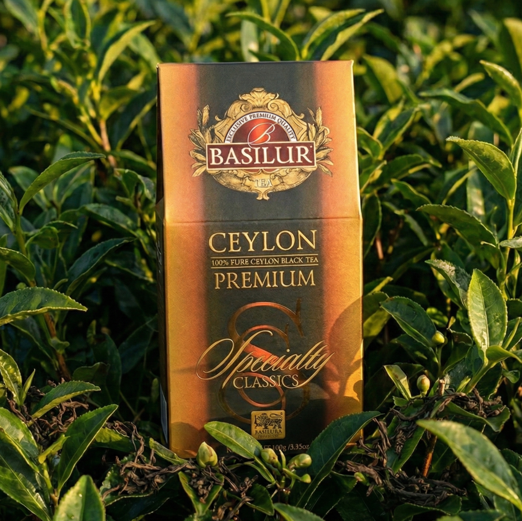 Opakowanie herbaty Basilur Ceylon Premium stojące wśród zielonych krzewów herbaty na plantacji, naturalne światło.