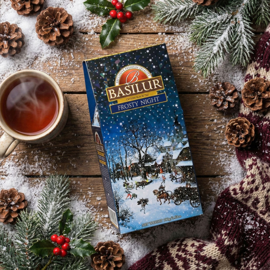 Opakowanie herbaty Basilur Frosty Night na drewnianym stole, obok filiżanka herbaty, szyszki i świąteczne gałązki.
