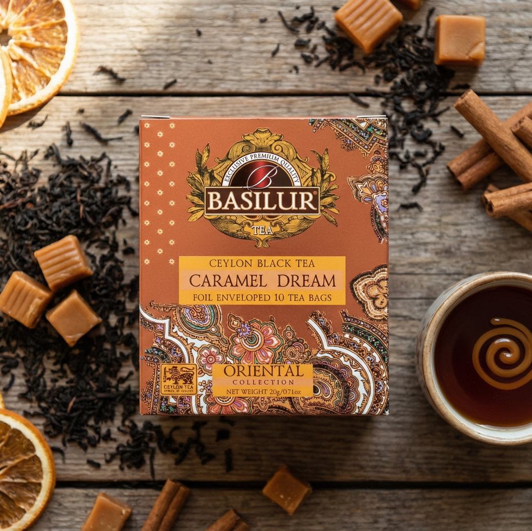 Opakowanie herbaty Basilur Caramel Dream, czarna herbata cejlońska z karmelem, obok filiżanka herbaty, cynamon i suszona pomarańcza