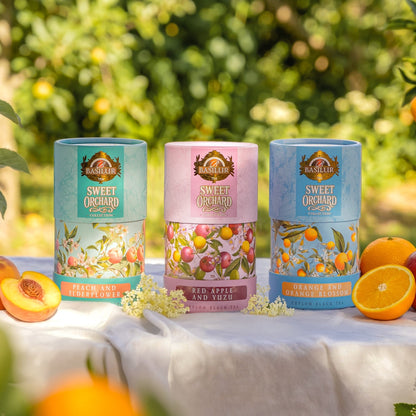 Trzy herbaty Basilur Sweet Orchard: Peach and Elderflower, Red Apple and Yuzu oraz Orange and Orange Blossom w ogrodowej aranżacji
