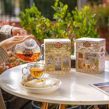 Herbaty Basilur Bloom Cafe Zesty Twist i Berry Twist obok filiżanki, dzbanka z naparem i deseru na stoliku