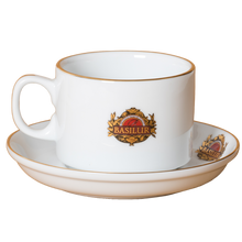 Filiżanka Basilur ze spodkiem, widok pod kątem, porcelana z logo i złotym rantem.