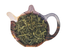 Liście organicznej chińskiej zielonej herbaty Bancha przedstawione na podstawce w kształcie czajniczka